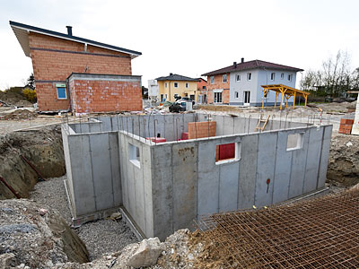 Eine Baustelle mit einem Betonfundament und mehreren umliegenden Gebäuden.
